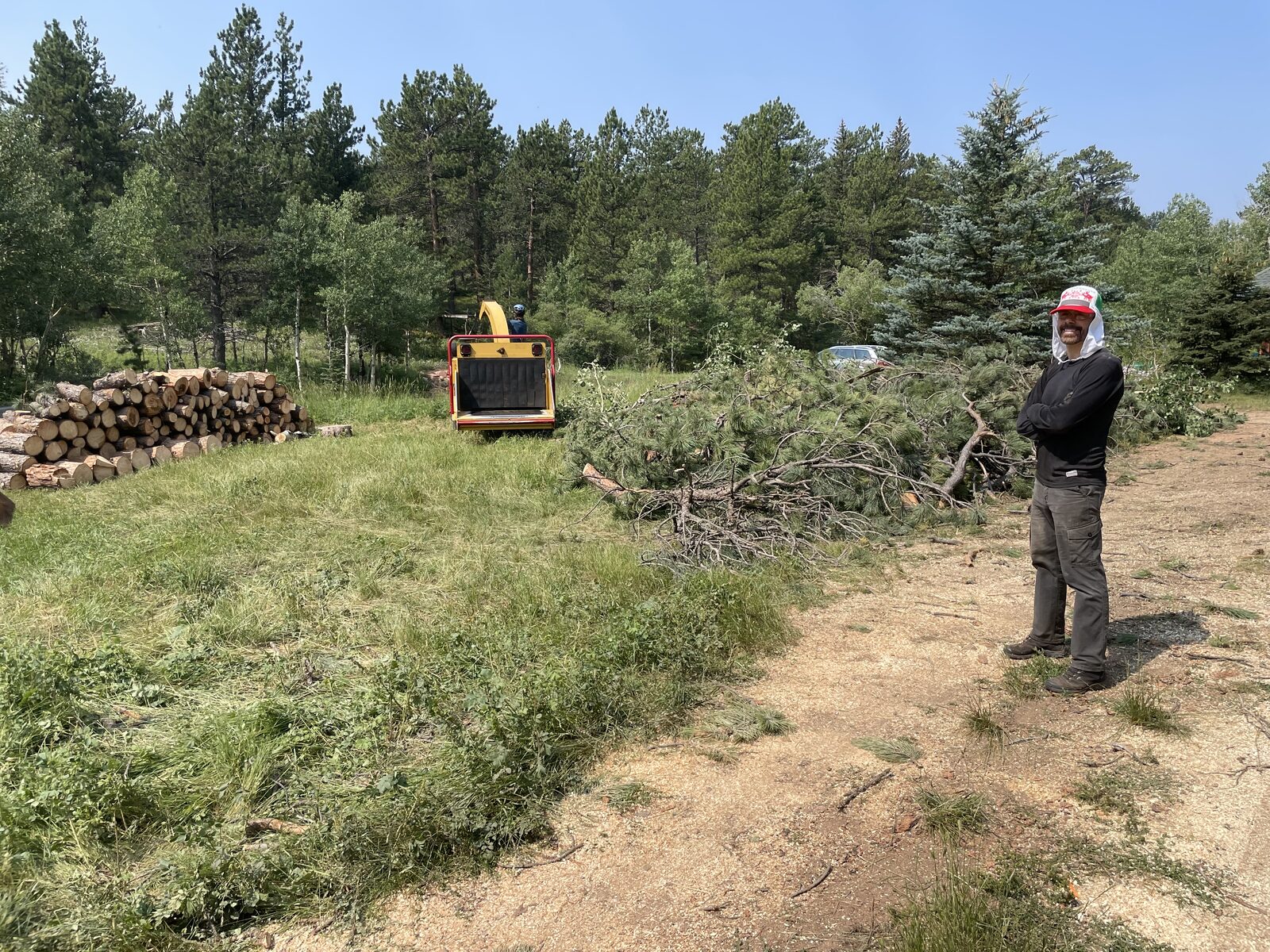 Crew running the chipper with cut pine brush and log rounds on site
